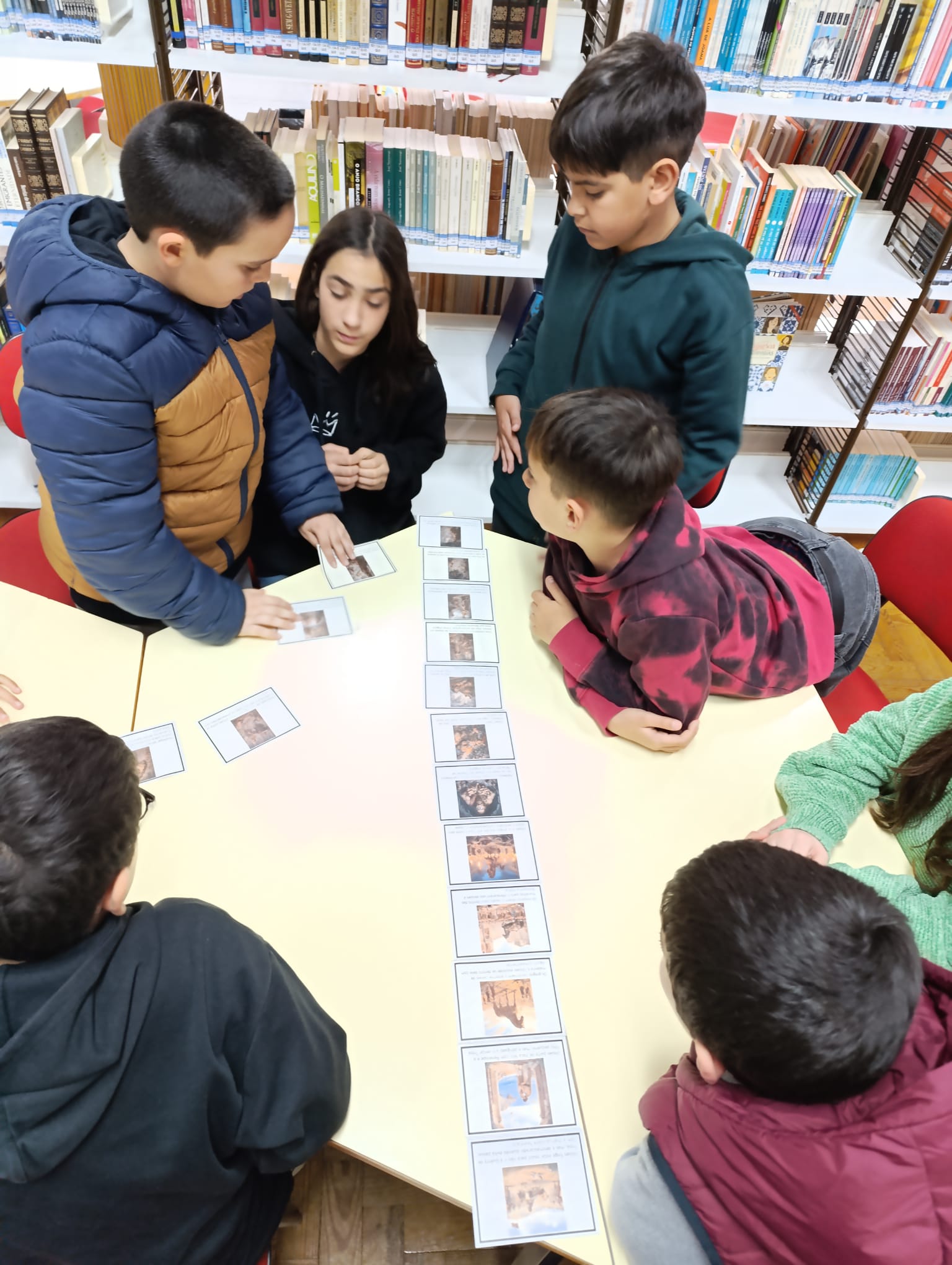 Alunos a explorar cartões da atividade na biblioteca