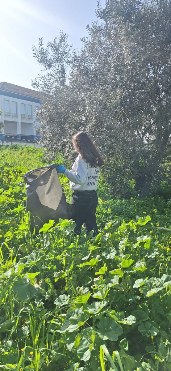 Aluna recolhendo lixo entre a vegetação