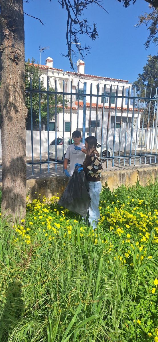 Dois alunos junto ao gradeamento com flores amarelas